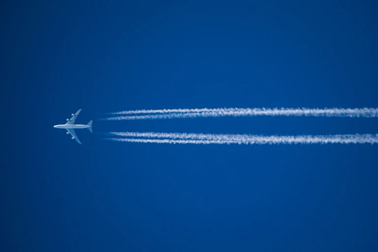 An aircraft leaving two trails behind it in the sky.