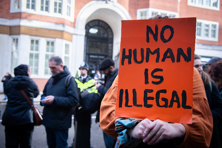Person holding sign saying 'no human is illegal'