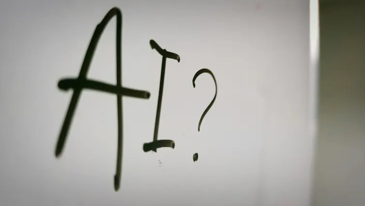 A white board with the word AI written on it followed by a question mark.