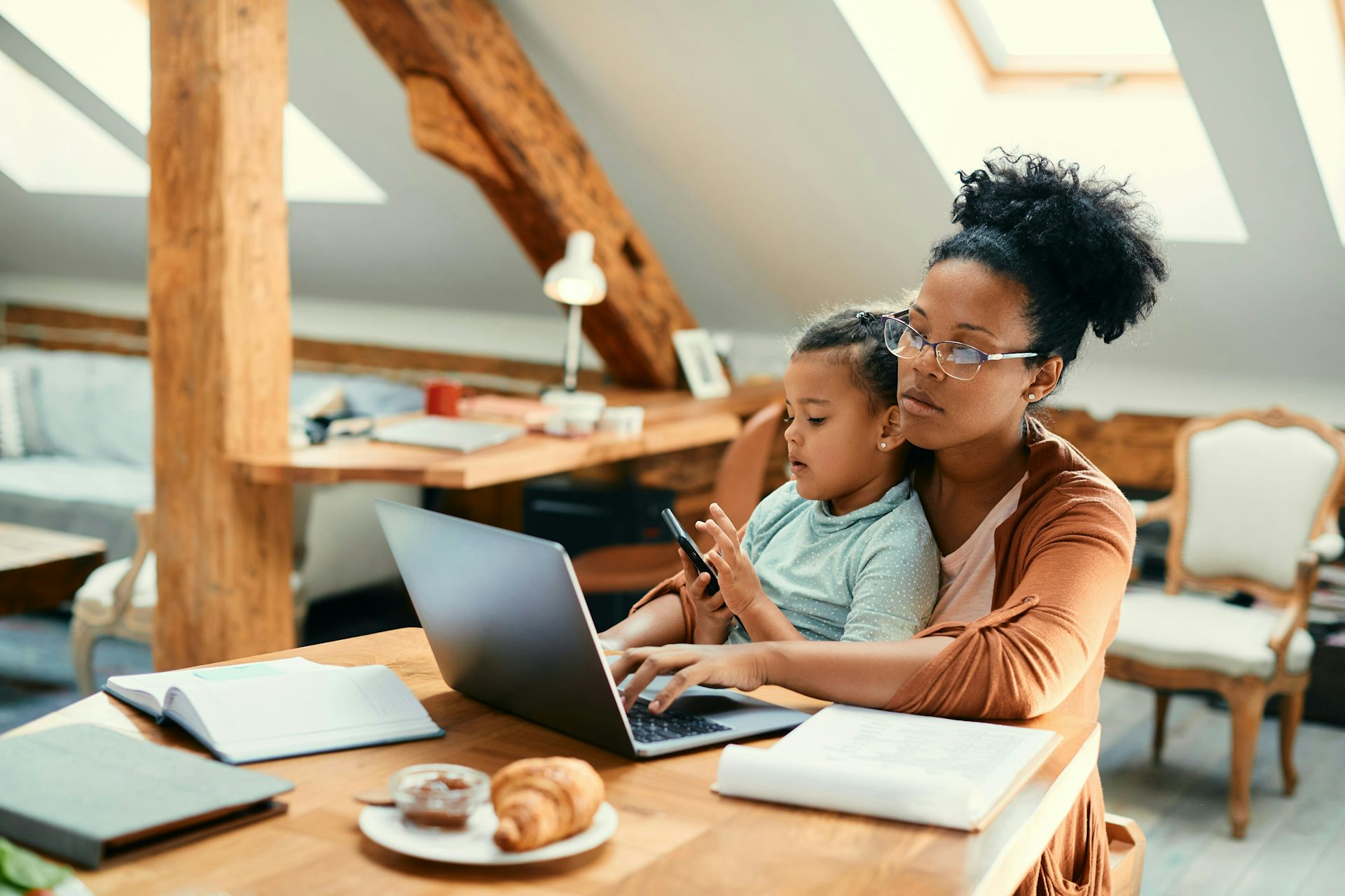 Una mujer trabajando en una computadora portátil mientras supervisa a un niño