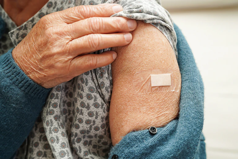 Older woman holds her t-shirt sleeve up to get vaccinated