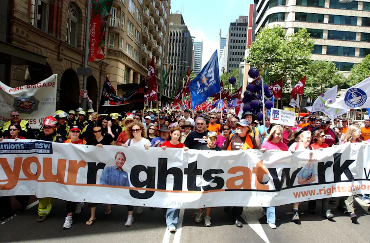 A large banner saying your rights at work with a large crowd of marching protesters behind it