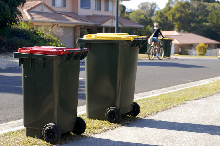 Two wheelie bins, one with a red lid, the other with a yellow lid