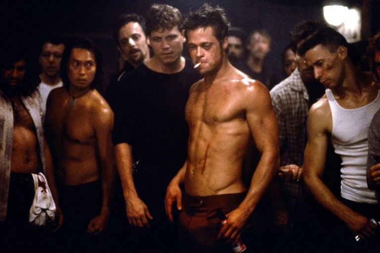 Brad Pitt shirtless with a cigarette in mouth, surrounded by brawlers