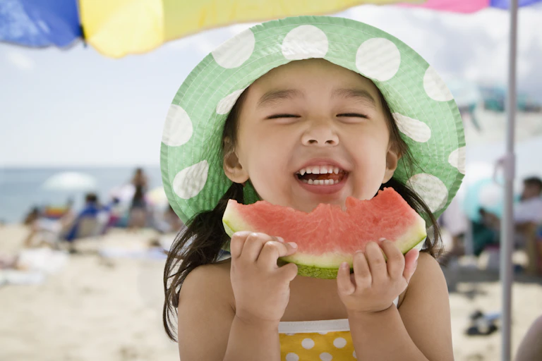 Smiling little girl eating watermelon.
