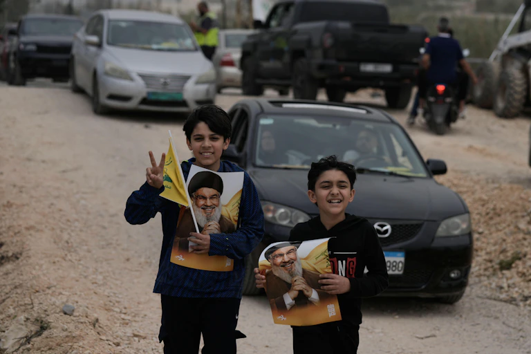 Two young boys wiith pictures of assassinated Hezbollah leader, Sayyed Hassan Nasrallah, as they walk across a destroyed bridge in south Lebanon.