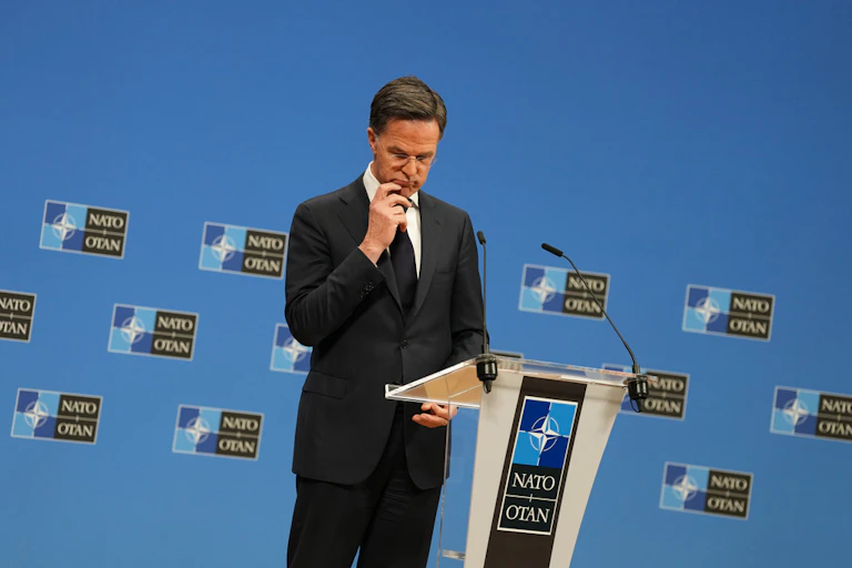 A man in a suit stands at a lectern.