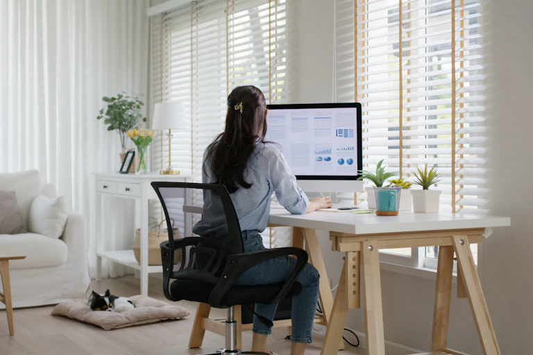 A woman seen from behind, working at a desk at home