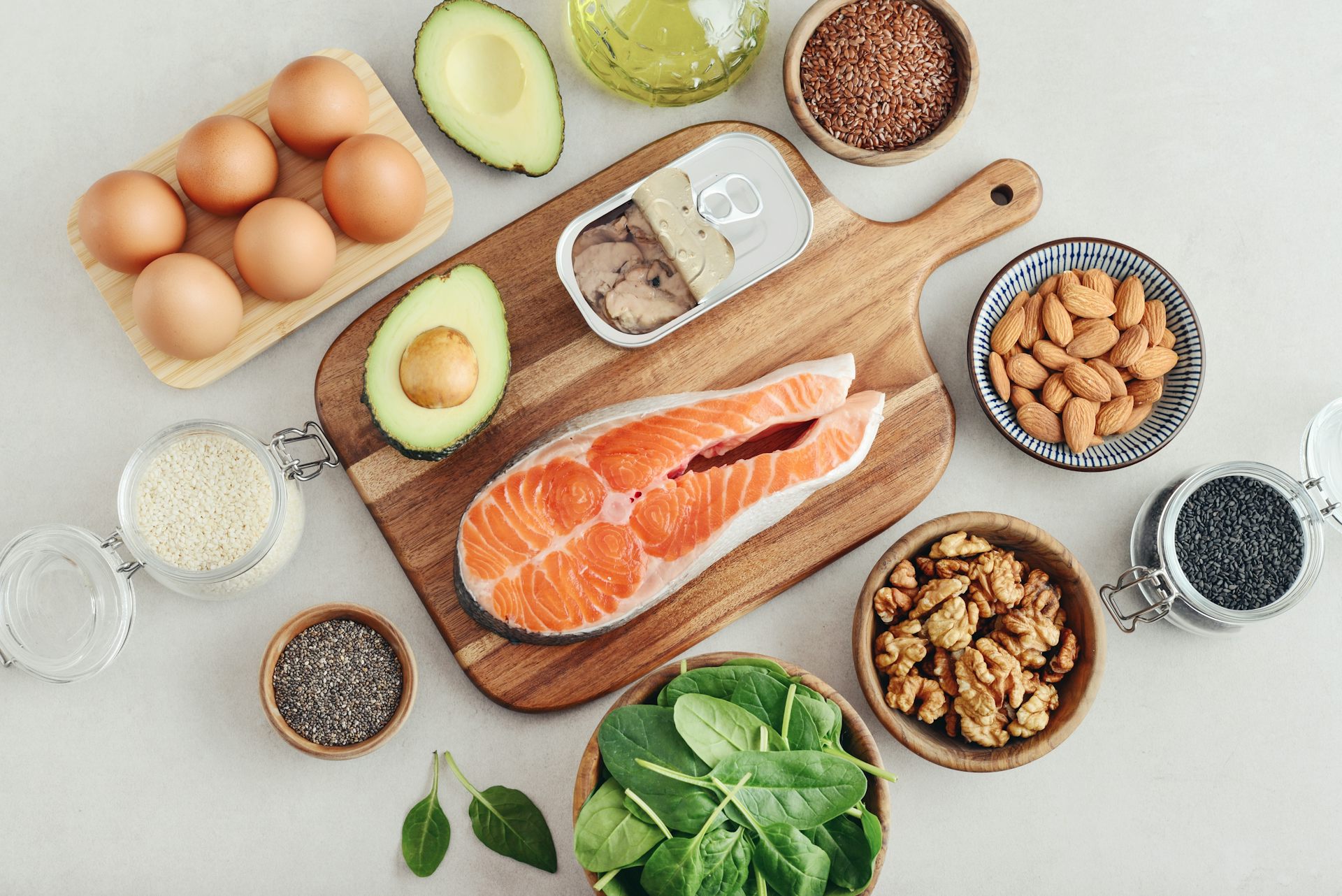 An overview of omega-3 rich foods laid out on a table, including salmon, sardines, eggs and nuts.
