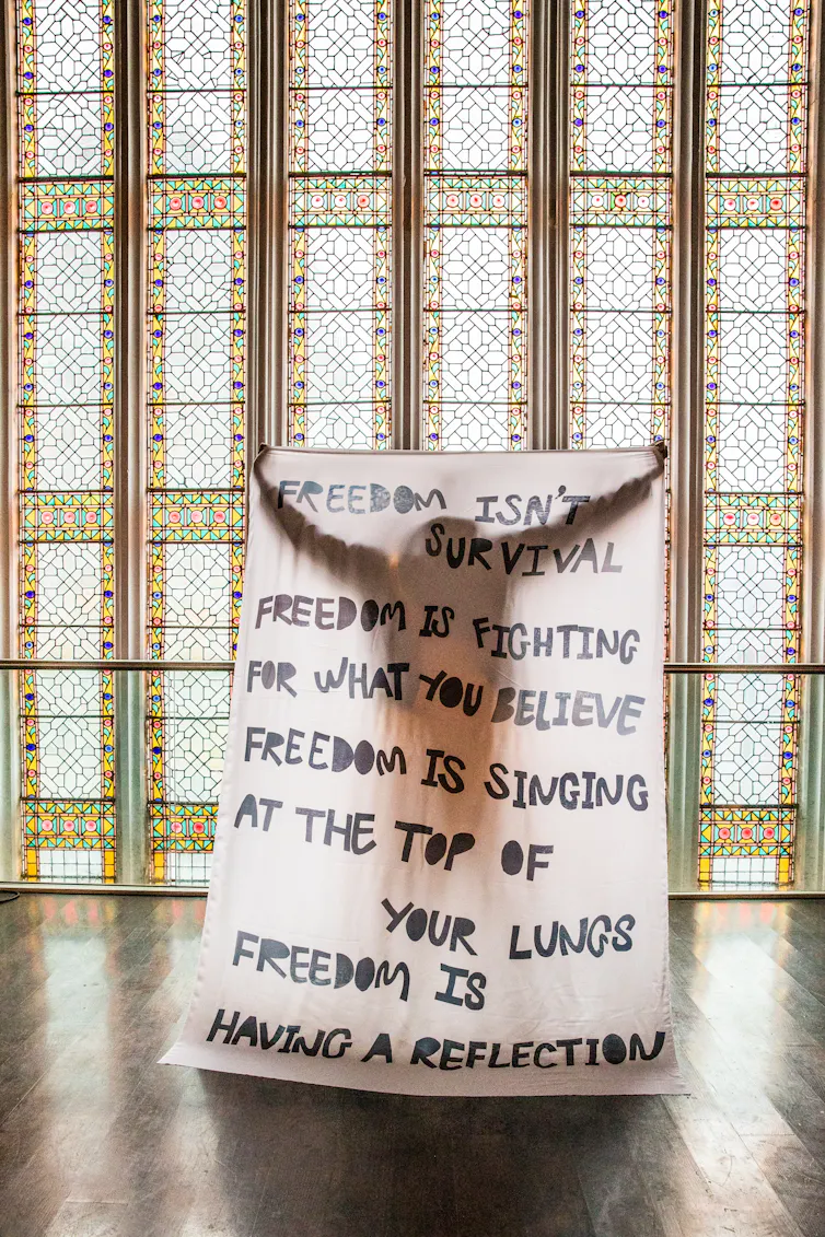 A woman holding a tapestry that says freedom is having a reflection