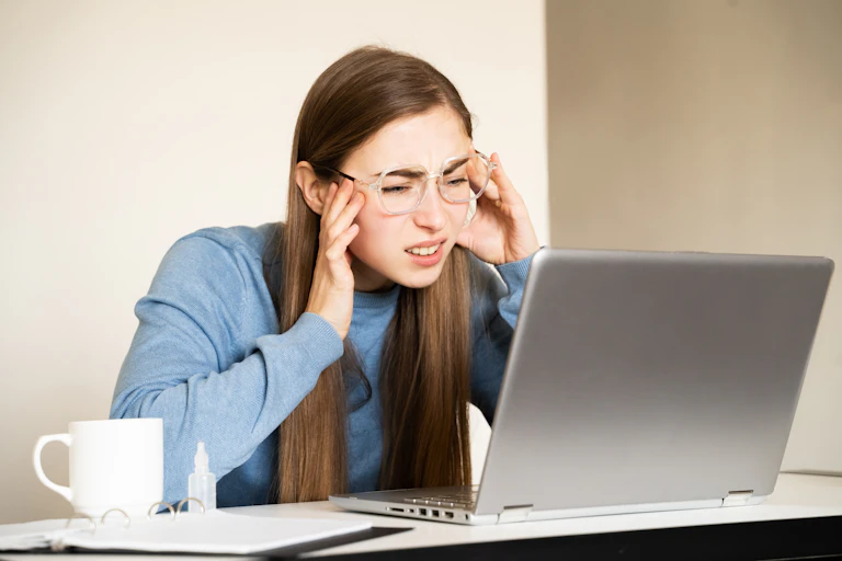 A woman stares at a laptop screen.