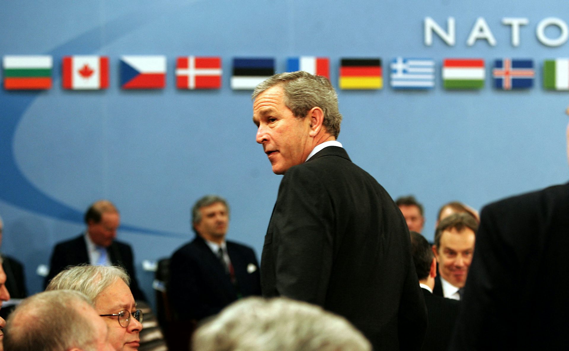 A man stands and looks around during a meeting.