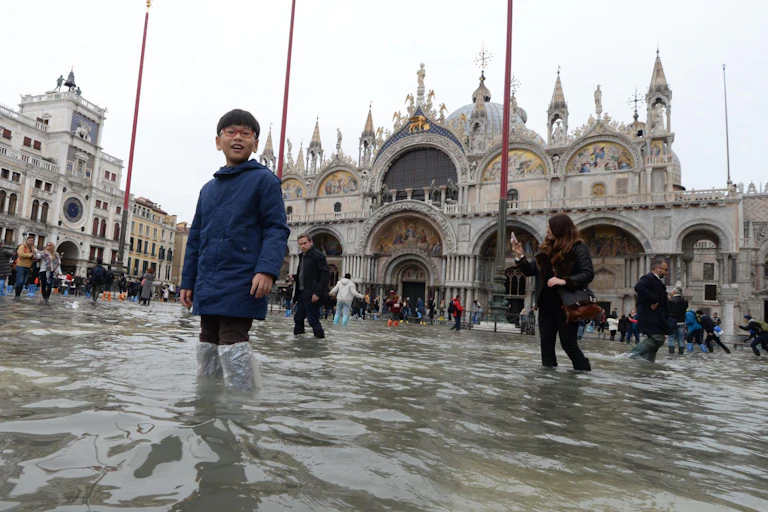 Boy stands in floodwaters in Piazza San Marco, Venice