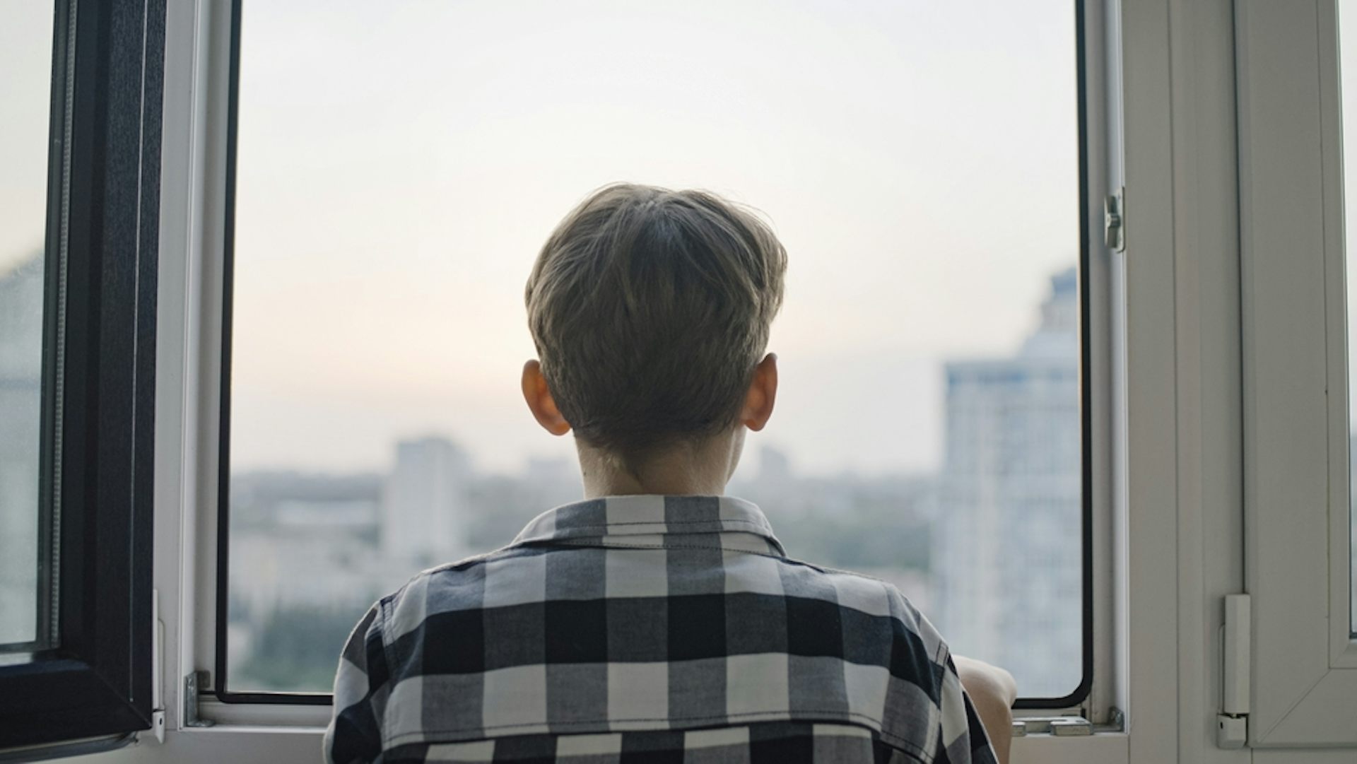 Un adolescent qui regarde par la fenêtre. 