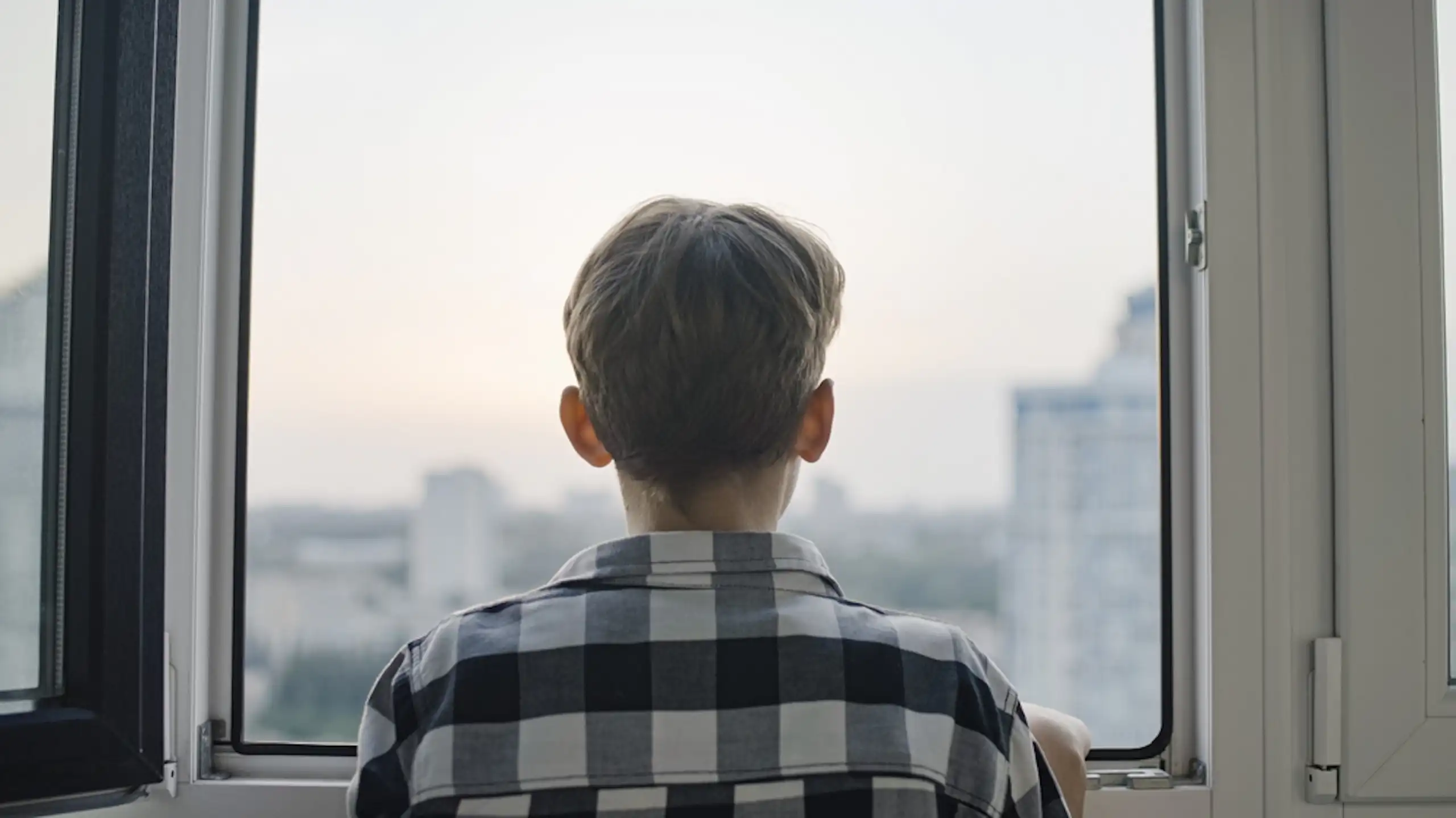 Un adolescent qui regarde par la fenêtre.