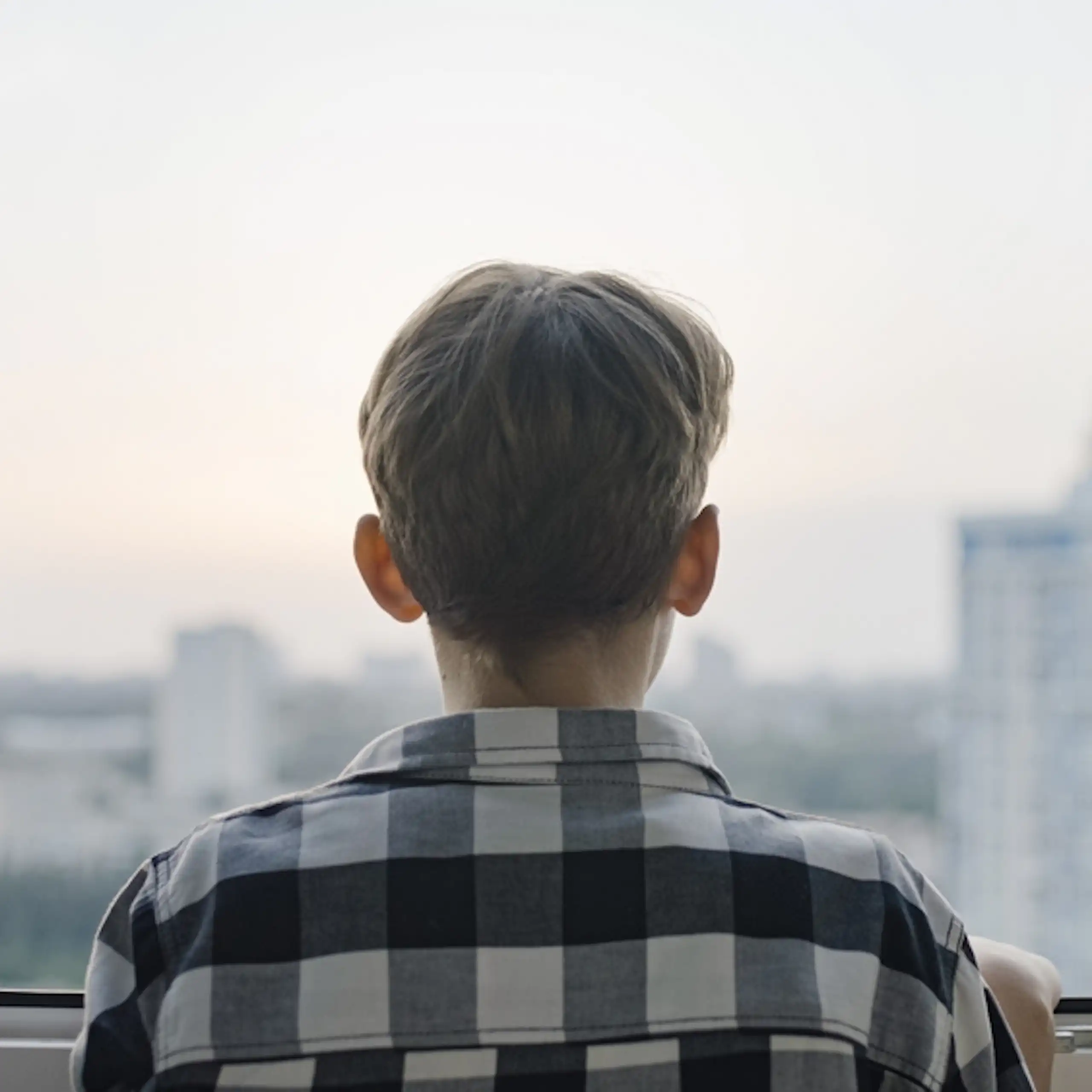 Un adolescent qui regarde par la fenêtre.