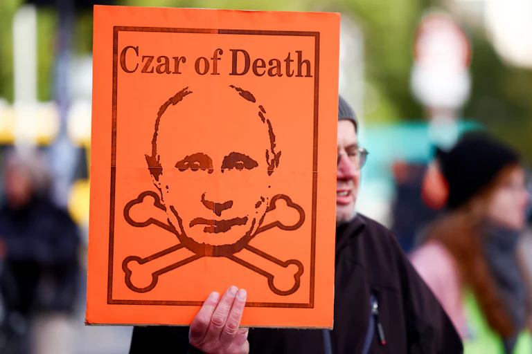 A man holds a placard that labels Vladimir putin the 'czar of death' during an anti-war demonstration in Berlin.