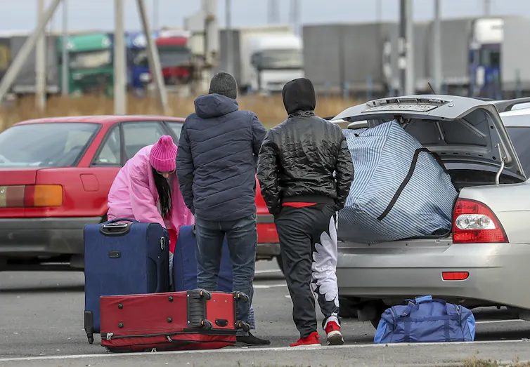 Three Russians handle their luggage at the Russia-Kazakhstan border.