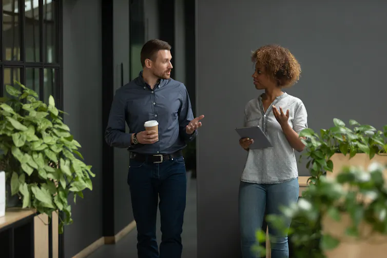 man and woman walking through a workplace having a conversation.