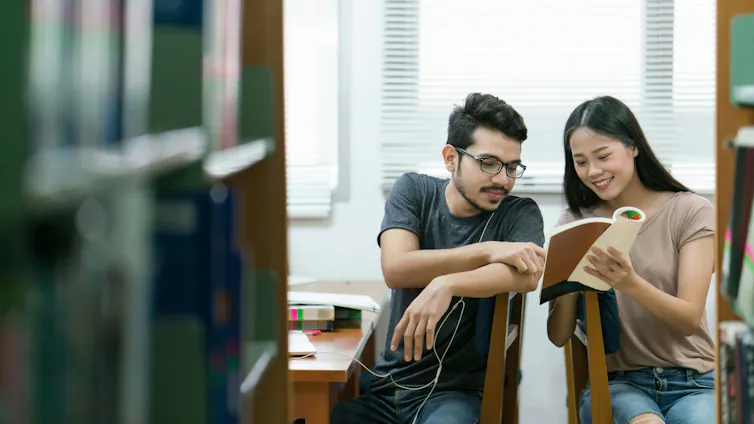 Two student seen in conversation at a library.