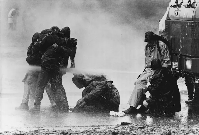Men and women are sprayed by a water cannon.