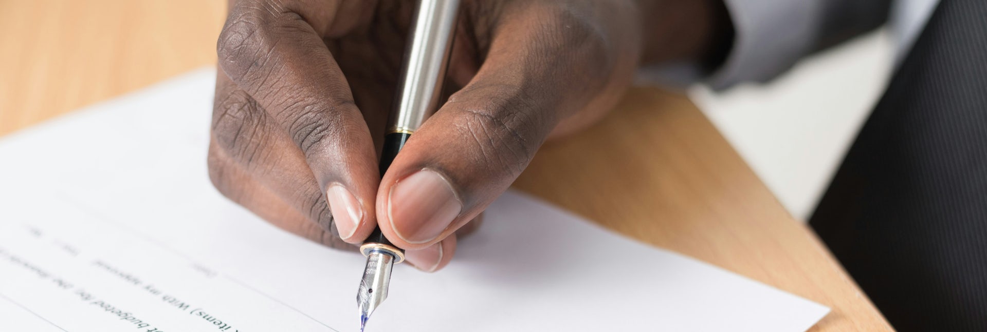 A Black person's hand seen holding a pen to paper. 
