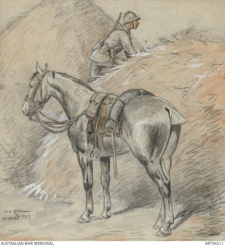 A soldier in a haystack with a horse behind him