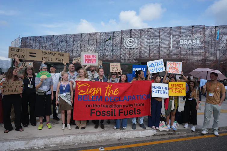 people at a potest hold a banner reading: sign the belem declaration on the transition away from fossil fuels