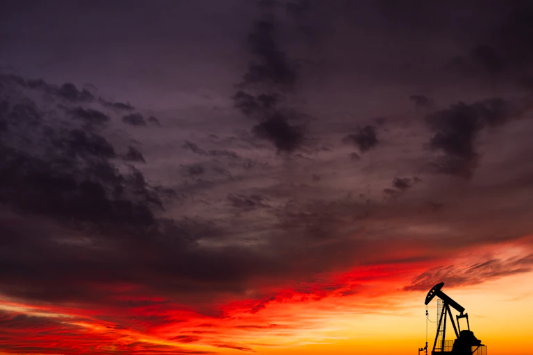 single oil pump-jack against sunset sky.