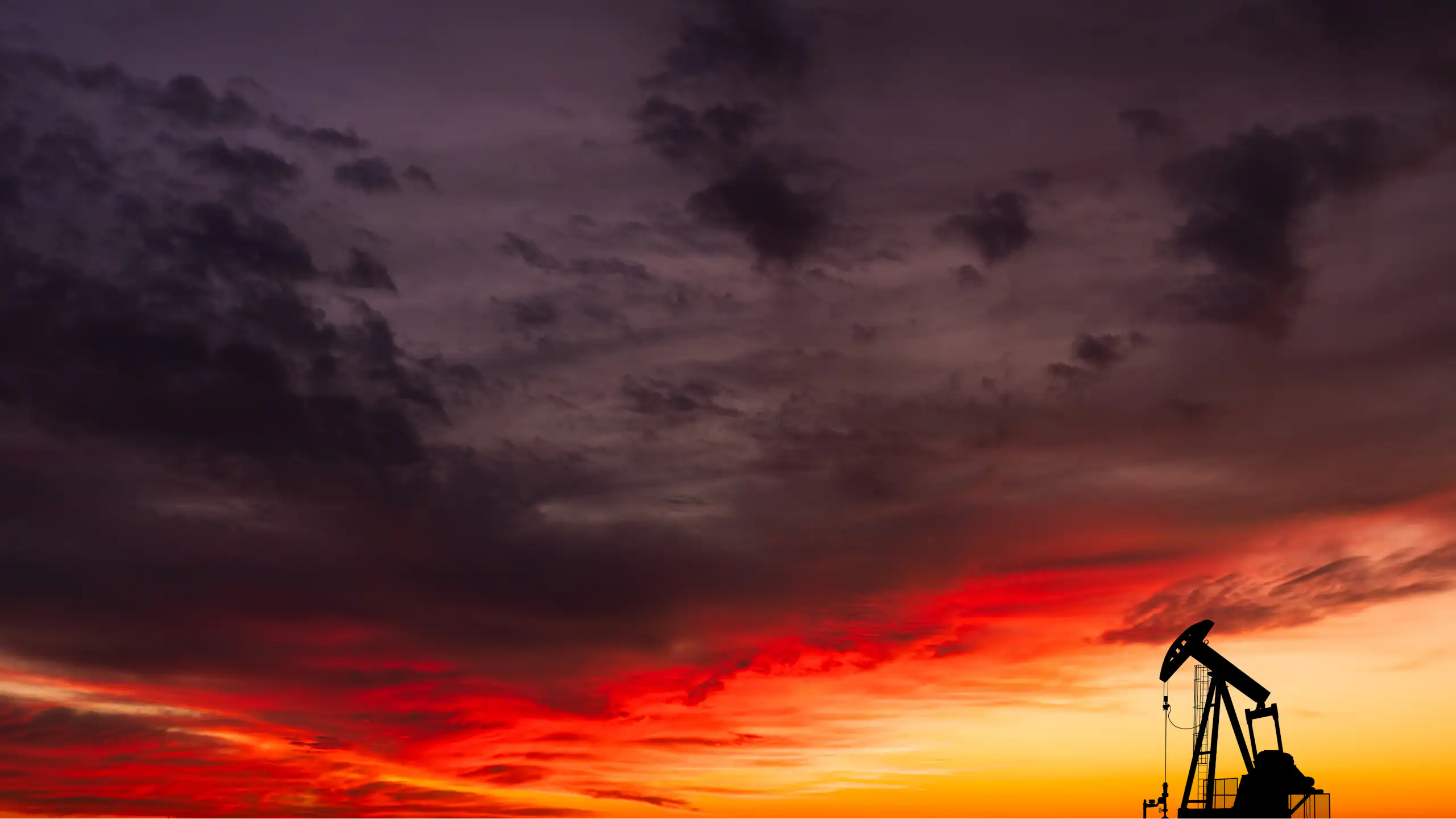 single oil pump-jack against sunset sky.