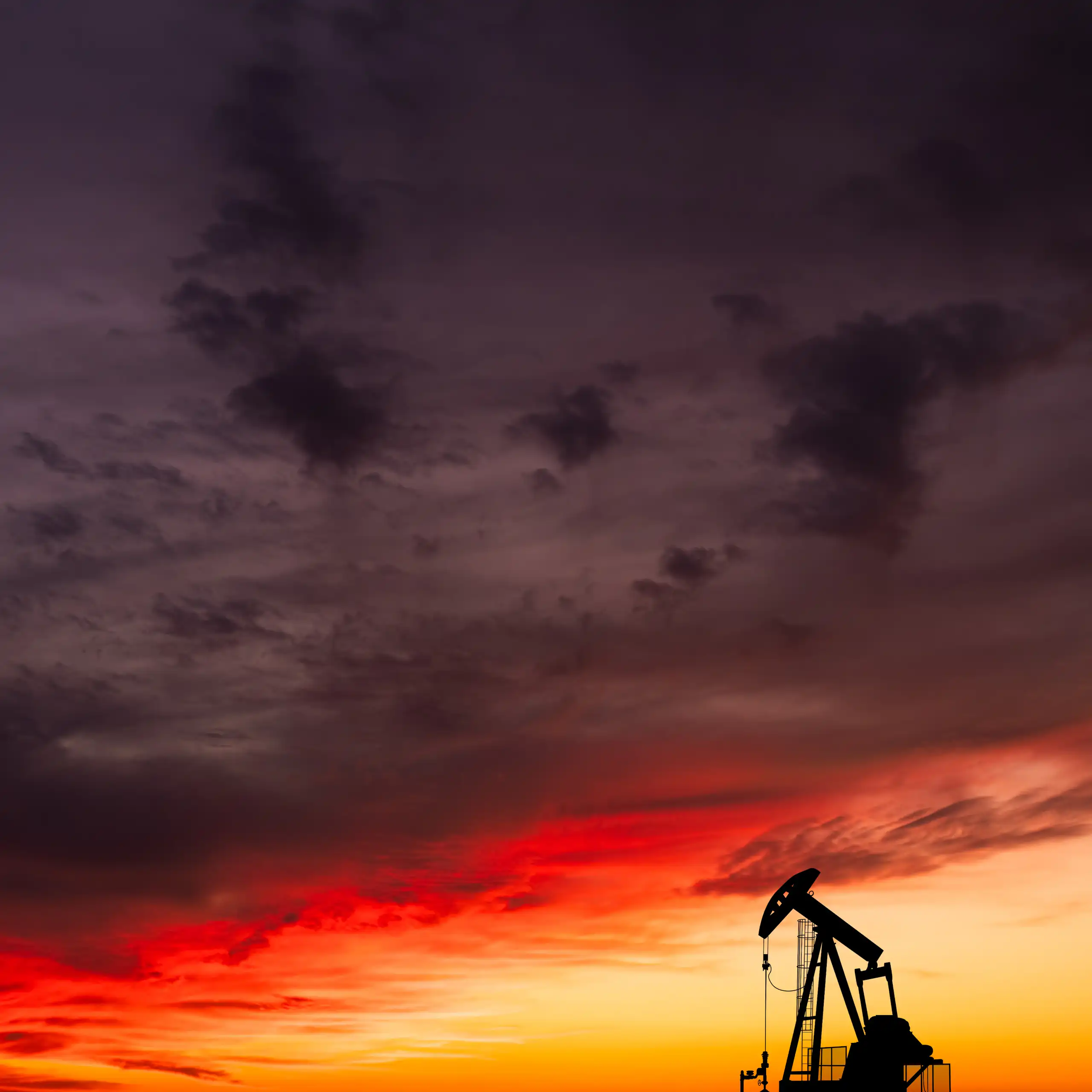 single oil pump-jack against sunset sky.