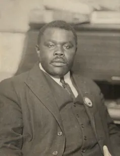 A Black man in a suit, vest and tie, with a moustache