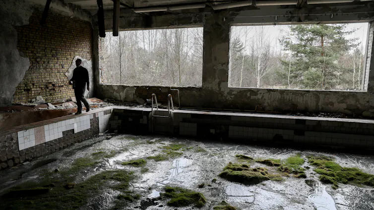 A man in a deserted swimming pool, forest outside