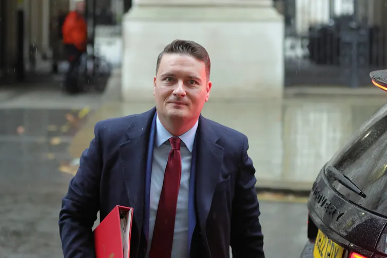 Health secretary Wes Streeting carrying a red binder.
