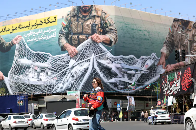 A poster in Tehran shows Iranian fighters holding a net over the Strait of Hormuz reading 'The Strait of Hormuz remains closed'
