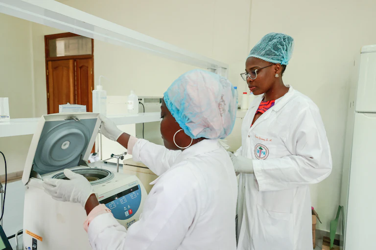 Two women wearing white coats, caps and gloves in a laboratory