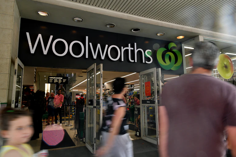 Blurred foreground images of shoppers outside a Woolworths store