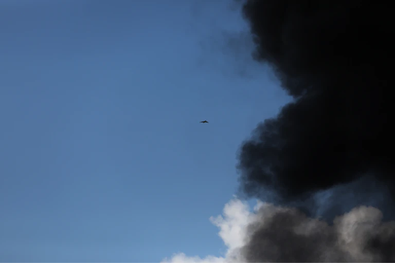 A drone is seen in the sky partly covered by black smoke.