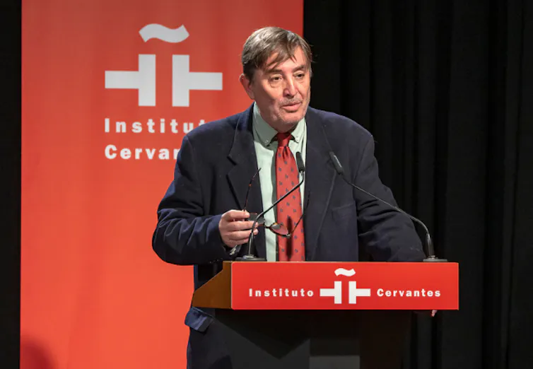 Un hombre habla tras un atril con el logo del Instituto Cervantes.