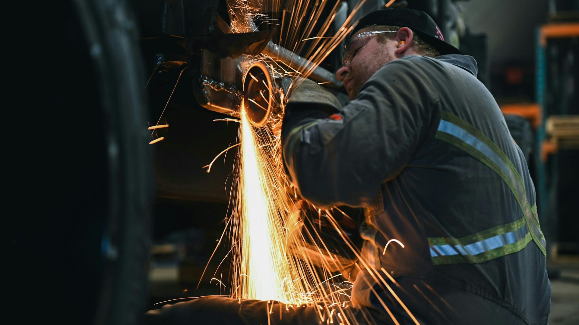 Un travailleur de la construction porte des bouchons d'oreille en utilisant une scie à métaux.