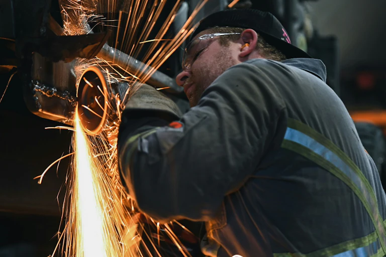 Un travailleur de la construction porte des bouchons d'oreille en utilisant une scie à métaux.