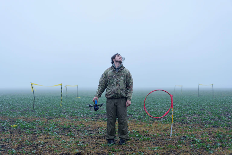 a young man stands in a misty field with a drone in his hand and his head tossed back