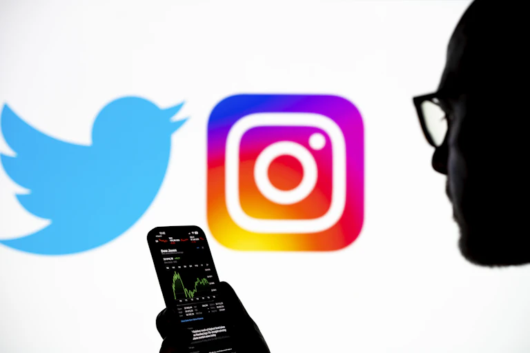 An illustration photo displays the Twitter and Instagram logos as well as a silhouetted image of a person holding a smart phone.