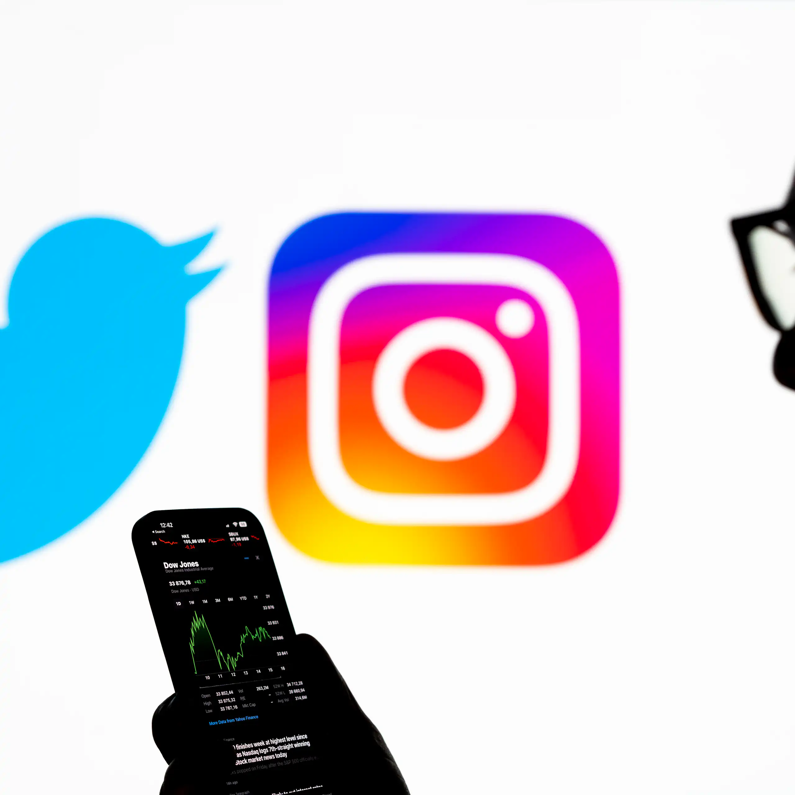 An illustration photo displays the Twitter and Instagram logos as well as a silhouetted image of a person holding a smart phone.