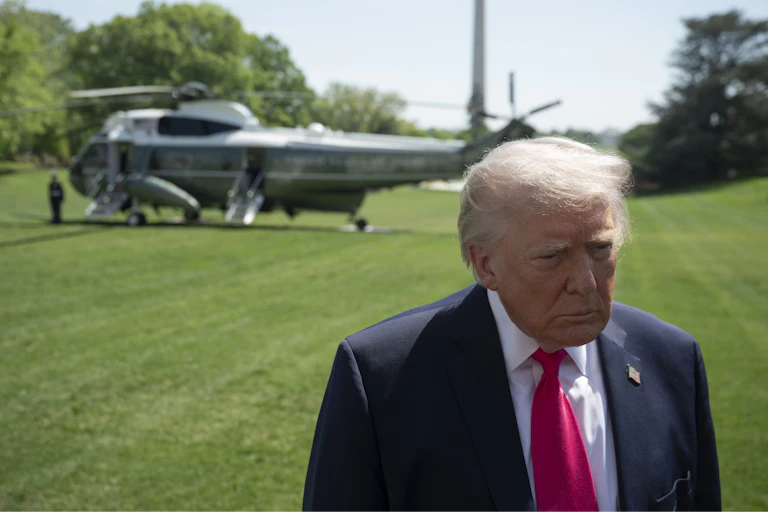 A man in a suit stands in front of a helicopter.