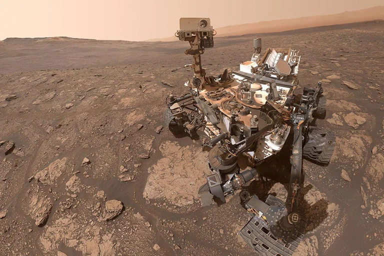 NASA's Curiosity rover robot on the brown, rocky surface of Mars