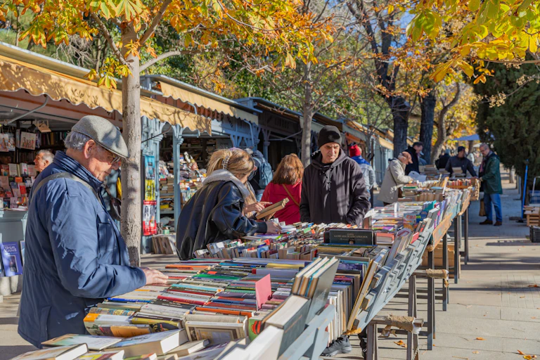 Gente revisando libros en los puestos de segunda mano en la Cuesta de Moyano de Madrid.