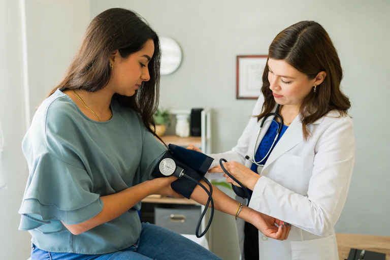 A woman has her blood pressure taken by a female doctor.
