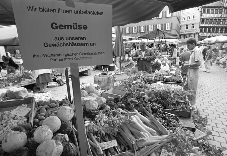 Vegetables are seen at a market with a German sign.