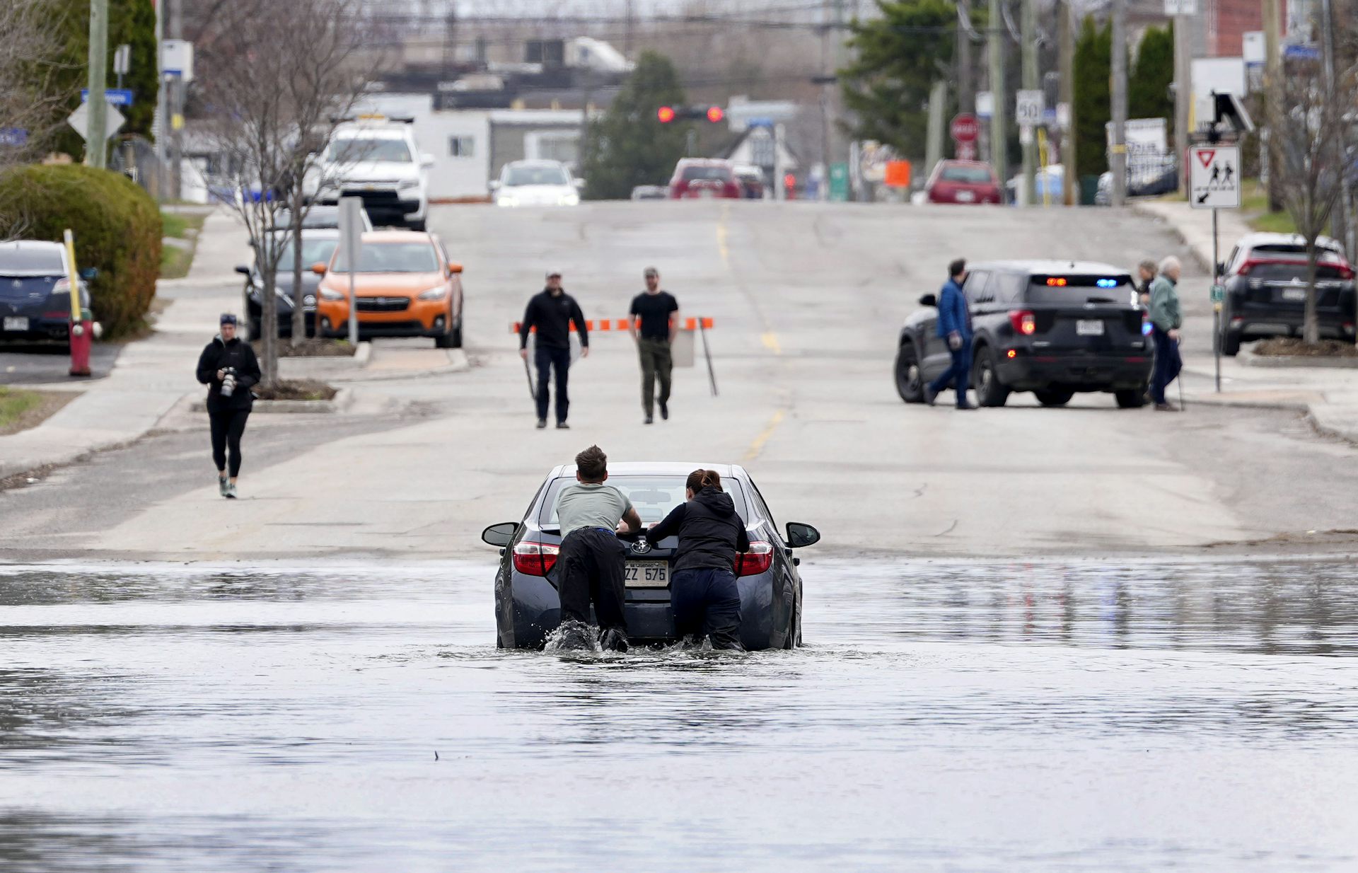 Deux jeunes adultes poussent une voiture hors d'une rue inond&eacute;e
